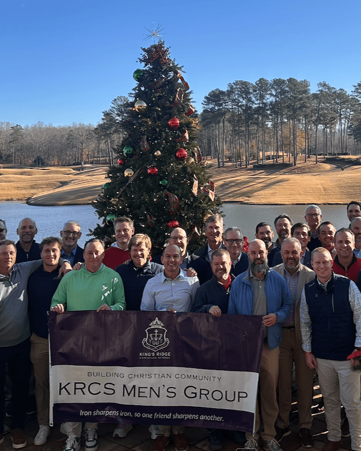 KRCS Men's Group members gathered for the annual Christmas breakfast in front of a decorated tree and lake